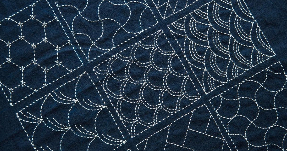 Traditional Japanese sashiko stitching in white thread on indigo cotton with wave and hexagon patterns