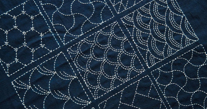 Traditional Japanese sashiko stitching in white thread on indigo cotton with wave and hexagon patterns