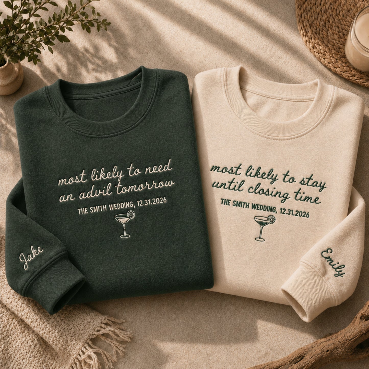 Two personalized crewneck sweatshirts laid flat on a beige fabric surface. One sweatshirt is dark green with white script text reading 'most likely to need an advil tomorrow' and a small cocktail graphic, with 'Jake' on the cuff.