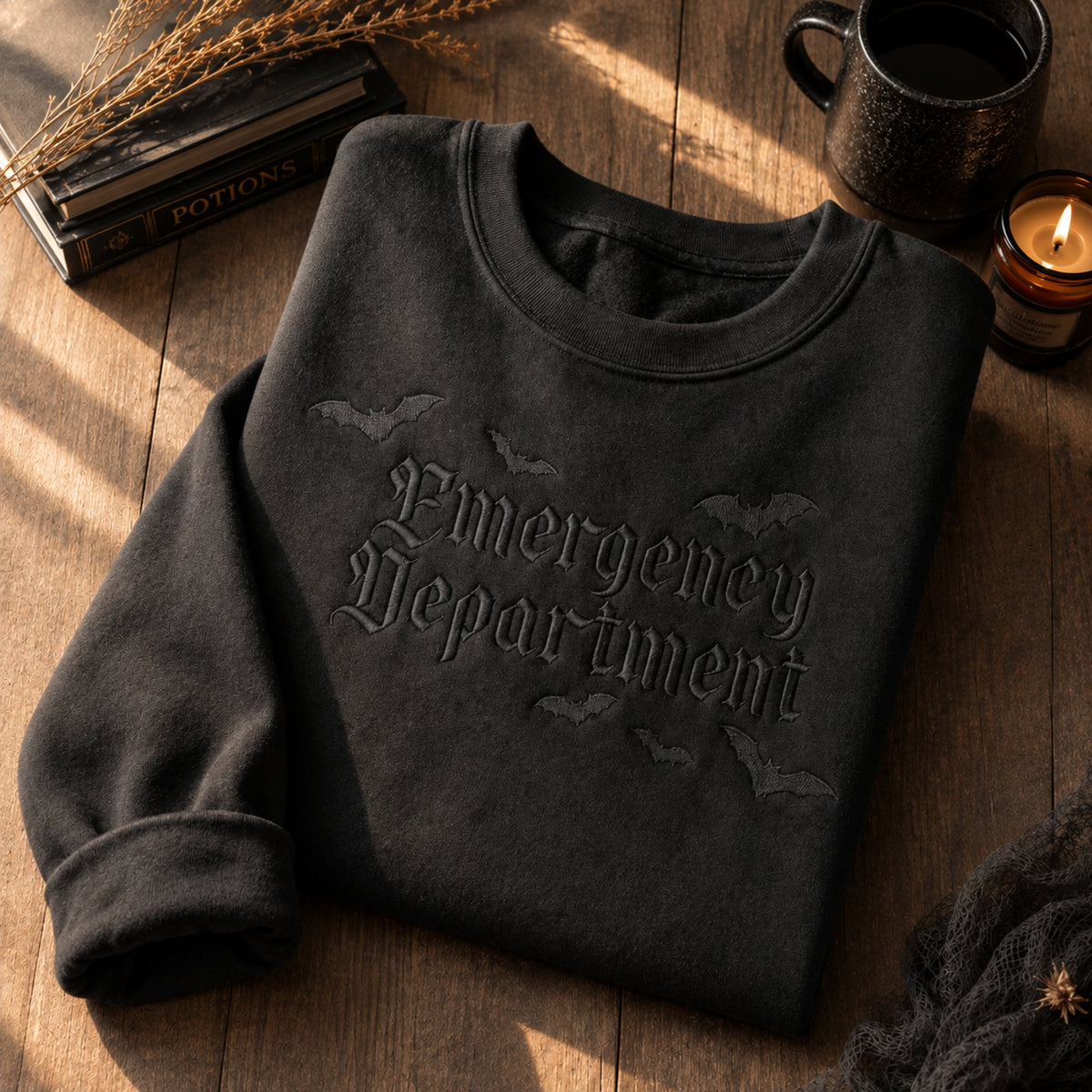 Black-on-black embroidered sweatshirt featuring a subtle gothic-style “Emergency Department” design with bats.