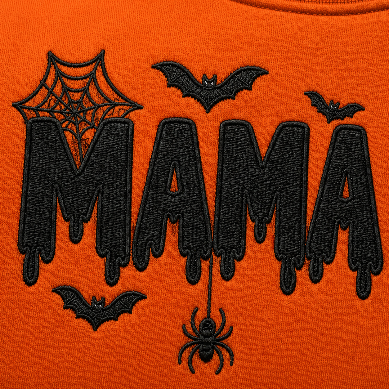 Detailed view of black dripping MAMA embroidery with bats and a dangling spider on a bright orange Halloween crewneck sweatshirt.