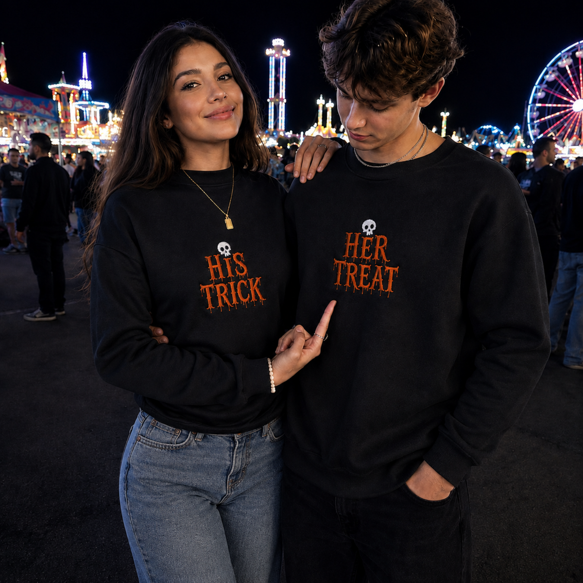 A man and a woman standing together at a nighttime fair, both wearing matching black crewneck sweatshirts with orange text reading 'His Trick' and 'Her Treat' with small skull graphics above.