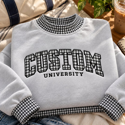 A light gray crewneck sweatshirt with black and white gingham patterned trim on the collar, cuffs, and hem, featuring 'CUSTOM UNIVERSITY' printed in black varsity lettering on the front.