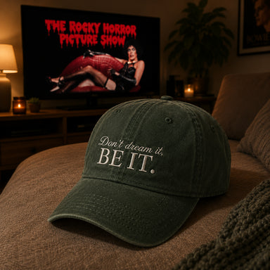 A dark green baseball cap with the embroidered text 'Don't dream it. BE IT.