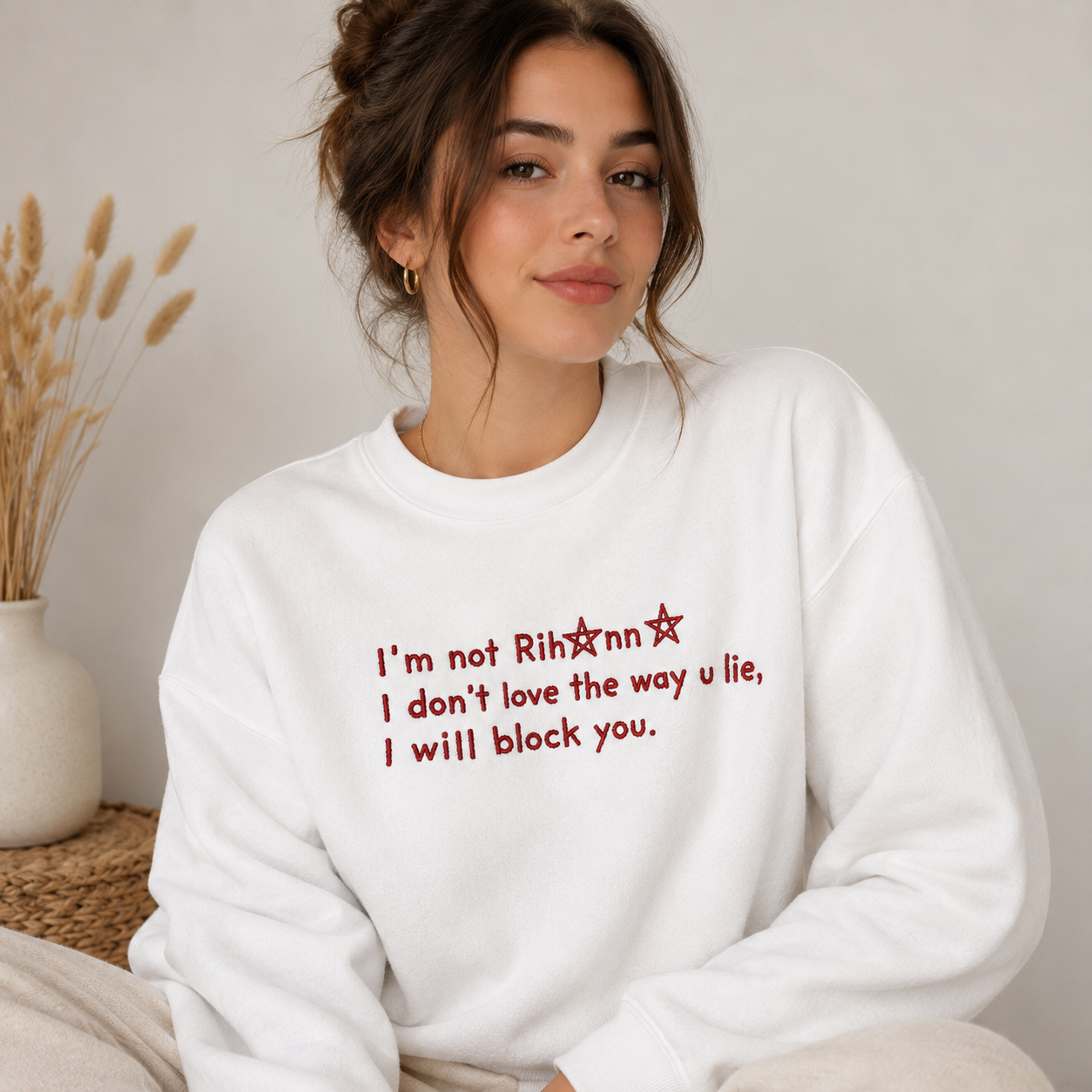Woman wearing a white crewneck sweatshirt embroidered with red text reading "I'm not Rihanna I don't love the way u lie, I will block you."